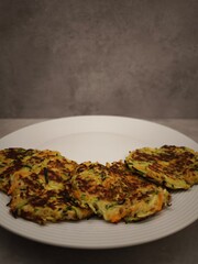 Delicious zucchini and carrot pancakes resting on a white plate