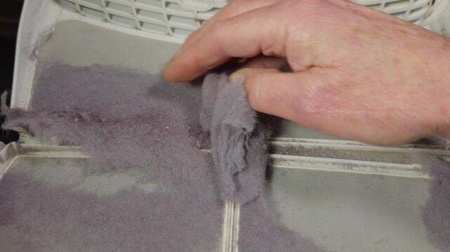 Closeup slow motion shot of a man&rsquo;s hand removing the build-up of garment lint fluff from the filter of a tumble dryer.