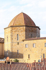 Duomo in Volterra with orange tiled dome under clear skies.