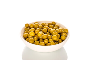 Canned green peas in a white ceramic dish, close-up, isolated on a white background.
