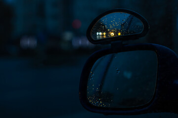Closeup of a cars rearview mirror with raindrops on it