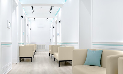 Modern waiting room with beige armchairs, light blue accents, and white walls, clean and minimalistic design, bright lighting, comfortable seating, suitable for medical or professional offices.