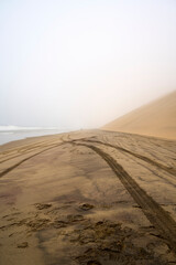 Car tracks in the sand on the road from Walvis Bay to Sandwich Harbour, where the sand dune meets the ocean