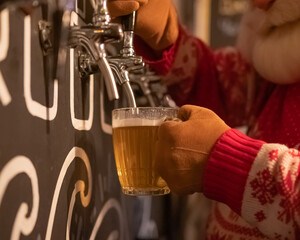 Santa Claus pouring beer from a keg at a bar. 