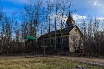 A small church with a bell tower and a cross on the front lawn