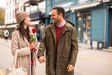 A mid adult Caucasian male surprises his partner with a single red rose on Valentine's Day.