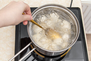 Woman stirs dumplings during cooking. Cooking dumplings
