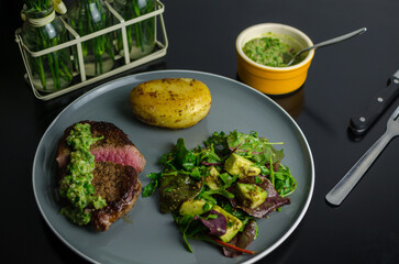 Medium rare beef steak with homemade Argentian style chimichurri, fondant potato and avocado salad