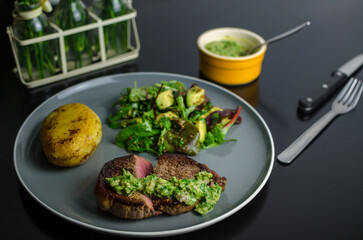 Medium rare beef steak with homemade Argentian style chimichurri, fondant potato and avocado salad