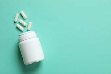White pills pouring out of medicine bottle on colorful background