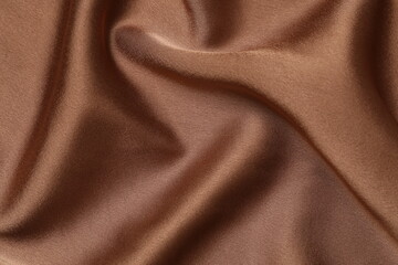 Brown silk satin. Shiny smooth fabric. Soft folds. Luxury background with space for design. Flat table, top view