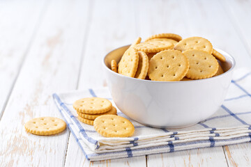 Delicious round crackers in a plate with on a light kitchen table, selective focus.