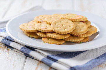 Salted crackers round shape in a ceramic bowl on a white table, selective focus.