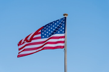  American flag waving in the wind. Stars and Stripes against a blue sky. Symbol of freedom.