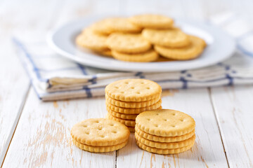 Stack of saltine round crackers on a white table, selective focus.