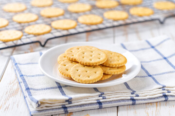 Freshly baked wheat round crackers cooling on a black wire rack, with in a light kitchen table, selective focus.