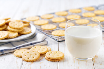 Salted crackers round shape and glass milk on a light kitchen table, selective focus.