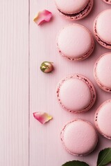 Obraz premium Delicate pink macarons arranged with fresh roses on a wooden surface