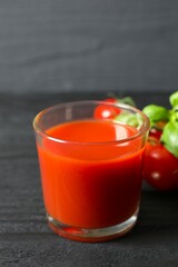 Tomato juice in a glass and fresh tomatoes on the table