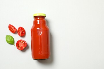 Tomato juice in a glass bottle and fresh tomatoes on white background