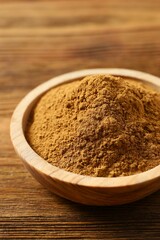 Cinnamon powder in a plate on a wooden background
