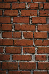 Fototapeta premium A detailed close-up of a red brick wall with weathered textures and cracks.