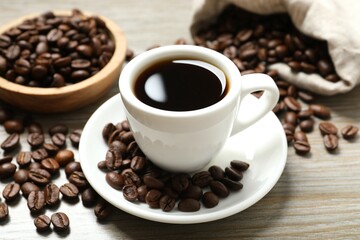 Cup of coffee and coffee beans on wooden background