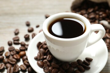 Cup of coffee and coffee beans on wooden background