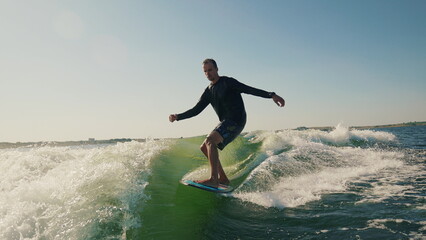 A wakeboarder performs exciting tricks on his board, moving quickly through the water. The footage shows smooth turns, jumps and acrobatics, highlighting the athlete's skill and endurance. Ideal for t