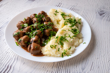 Swedish Meatballs with Gravy Sauce on a plate with mashed potatoes on a wooden background