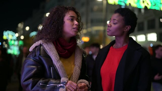 Two young women having a serious conversation at night