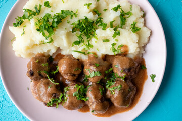Swedish Meatballs with Gravy Sauce on a plate with mashed potatoes on a wooden background