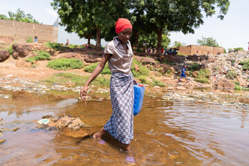 Young African girl crossing a flooded road after heavy rains; concept of climate change in third...