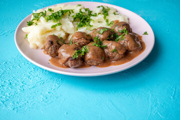 Swedish Meatballs with Gravy Sauce on a plate with mashed potatoes on a wooden background