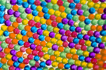 Hydrogel colored transparent balls orbeez, colorful background. Top view.