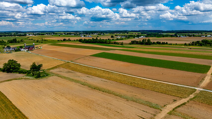 Expansive farmland stretches across the horizon, showcasing rich brown and green fields under a...