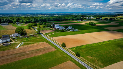 Obraz premium Vast agricultural fields dominate the landscape, showcasing a mix of green crops and brown earth.