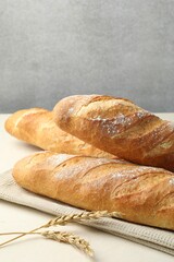 Fresh baguettes and spikes on beige table, closeup