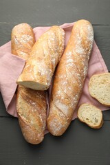 Cut fresh baguettes on grey wooden table, top view