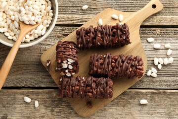 Delicious chocolate puffed rice bars on wooden table, flat lay