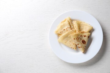 Delicious folded crepes on white wooden table, top view. Space for text