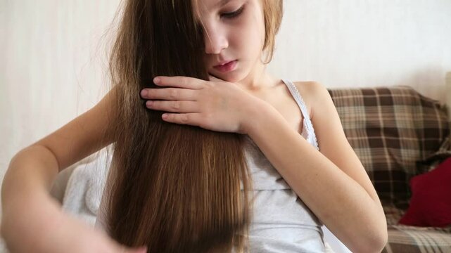 8 years old girl brushing her long hair in her room in the morning