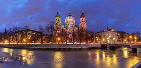 Fototapeta premium The illuminated St. Luke's Church in Munich, Germany, viewed from across the Isar River at night