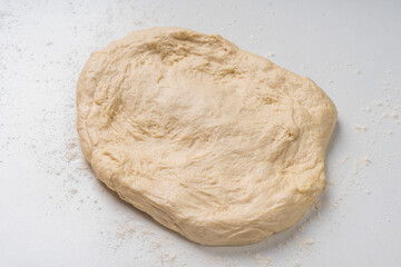 Yeast dough for a pie or pizza on a white table with flour. Pizza cooking process, recipe