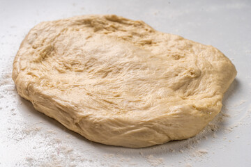 Yeast dough for a pie or pizza on a white table with flour. Pizza cooking process, recipe