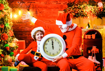Family winter holidays. New year midnight. Cute child boy and smiling bearded man in Santa costume...