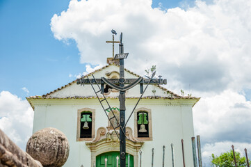 Inspiring image of the wooden rustic cross with symbolic elements such as the crown of thorns, the ladder and the cloth and the rooster and the church with the bells in the background