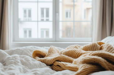 A wide shot of a person layering up with sweaters and scarves in a brightly lit bedroom