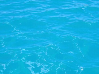 Close up of pure blue turquoise ocean water texture with foamy waves, marine, texture, blue