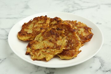 Delicious potato pancakes on white marble table, closeup